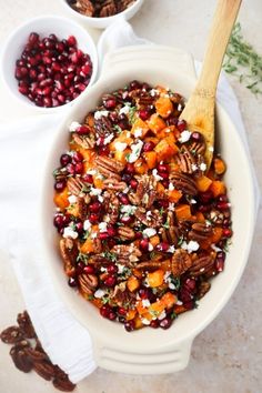 a white bowl filled with food next to two bowls of nuts and cranberries