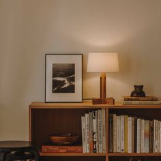 a bookshelf filled with lots of books next to a lamp