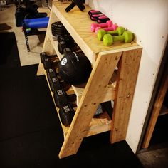 a wooden shelf filled with dumbs and exercise equipment next to a wall in a gym