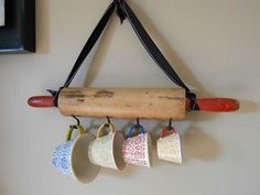 four cups hanging on a wall with a piece of wood attached to it