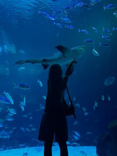 a woman standing in front of a large aquarium filled with fish