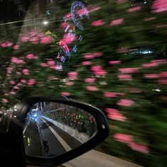 a car's rear view mirror is shown with pink flowers on the side of it