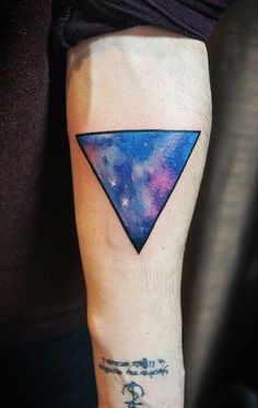 a person with a tattoo on their arm has a blue triangle and stars in the sky