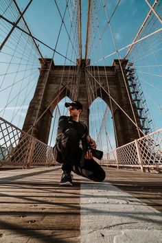 a man sitting on the ground in front of a bridge