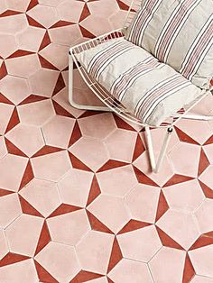 a chair sitting on top of a pink floor next to a cushion and pillow in the shape of hexagonal tiles