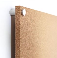 a close up of a cork board with holes in the middle and a white wall behind it