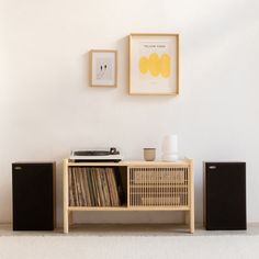 a record player sitting on top of a wooden shelf next to two speakers and a wall hanging above it