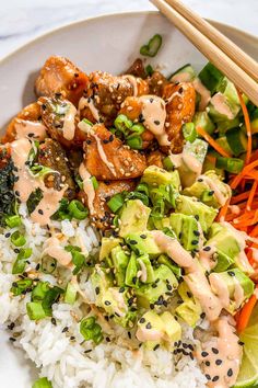 a white plate topped with rice, meat and veggies next to chopsticks