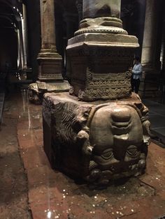 a large stone statue sitting in the middle of a room next to two tall pillars