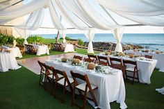 an outdoor dining area with tables and chairs set up for a formal function by the ocean