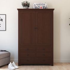 an armoire in a living room next to a couch and potted plant on top of it