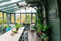 a dining room filled with lots of furniture and plants on top of it's windows