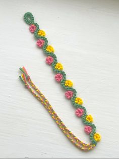 a crocheted bracelet with flowers on it and a string attached to the clasp