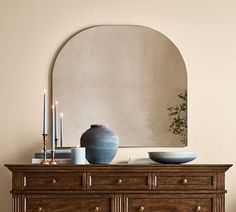 a table with a vase and candles on it next to a mirror in a room