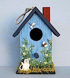 a blue birdhouse with a cat sitting in the grass