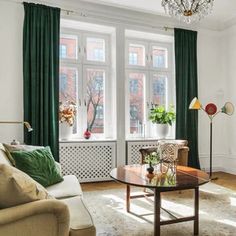 a living room filled with furniture and a chandelier hanging from the side of a window