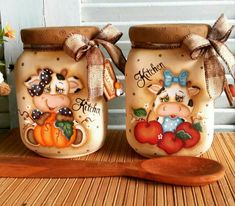 two ceramic jars with farm animals painted on them and a wooden spoon next to it