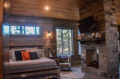 a bedroom with a stone fireplace and tv mounted to the side of the wall in front of it