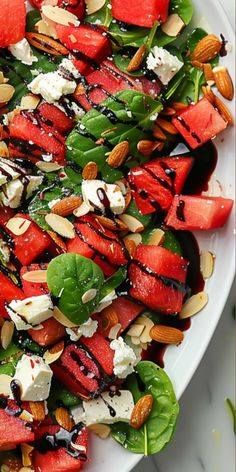 watermelon, spinach and feta salad with almonds on a white plate