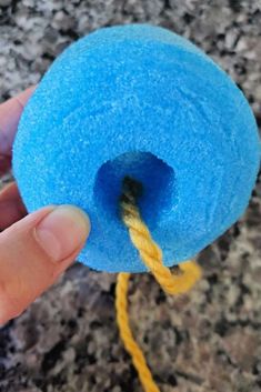 a person holding a blue ball of yarn in their left hand and the rope is yellow