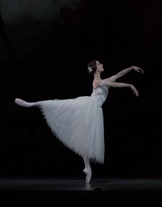 a ballerina in white is performing on stage