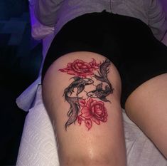 a woman laying on top of a bed with a tattoo on her thigh and two birds flying around