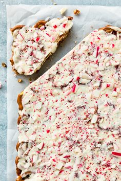 a piece of cake with white frosting and sprinkles on it sitting on top of paper