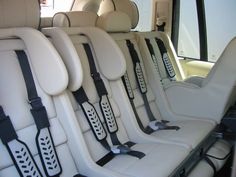 the interior of a vehicle with white leather seats and black straps on each armrests