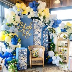 a blue and white wedding arch decorated with balloons, greenery, and other decorations