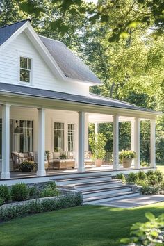 a white house with porches and steps leading up to the front door is surrounded by greenery