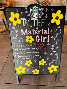 a sign that says try the material girl with flowers and hearts on it in front of a store