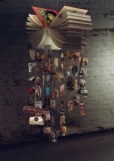 an open book hanging from the side of a brick wall next to a pile of books