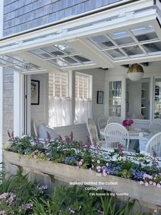 an outdoor patio with white furniture and flowers in the planter boxes on the porch