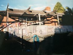 an old photo of a house with a fence in the foreground and a blue hose hanging from it's roof