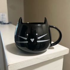 a black cat mug sitting on top of a counter