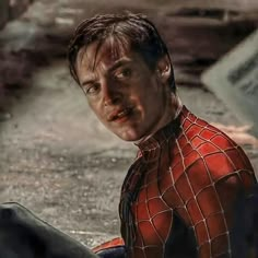 a close up of a person wearing a spiderman suit and sitting on the ground