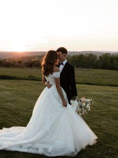 a bride and groom are standing in the grass