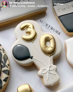 decorated cookies with gold and black decorations on top of a white tablecloth next to cookie cutters