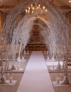 an aisle decorated with white branches and candles