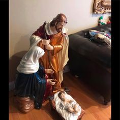 two statues of jesus and mary are on the floor in front of a black couch