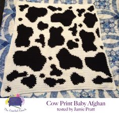 a crocheted blanket with black and white animal prints on it, sitting on top of a quilt