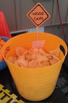 a yellow bucket filled with cheetos next to a sign that says wood chips