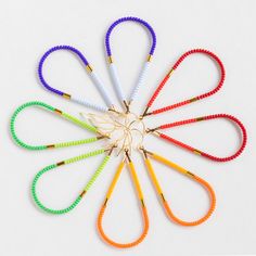 six different colored scissors are arranged in the shape of a flower on a white surface