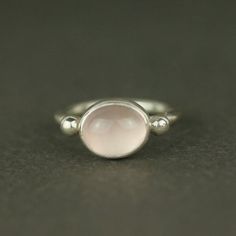 An ancient-inspired, light pink rose quartz oval ring. A rustic piece of gemstone jewellery.The soft pink stone is framed by two sterling silver studs on a satisfyingly chunky band. This design was inspired by ancient Roman rings and it has a beautifully rustic simplicity.Rose quartz is a symbol of universal love, heart opening and self love. Also available in chrysoprase or turquoise.• Sterling silver• Oval shaped, natural rose quartz gemstone• 5% of all profits go the the charity Help Refugees Pink Moonstone Sterling Silver Ring For Anniversary, Silver Rose Quartz Jewelry With Birthstone, Pink Sterling Silver Moonstone Promise Ring, Elegant Pink Moonstone Sterling Silver Ring, Pink Sterling Silver Spiritual Rings, Pink Oval Moonstone Ring In Sterling Silver, Pink Oval Jewelry With Bezel Setting, Pink Oval Bezel Set Jewelry, Delicate Pink Sterling Silver Rings