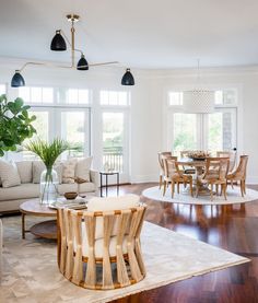 a living room filled with furniture next to a dining room table and chairs on top of a hard wood floor