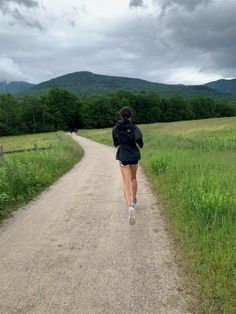 a woman is running down a dirt road