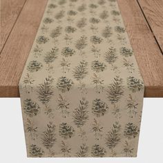 an image of a table runner on top of a wooden surface with flowers and leaves