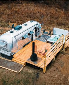 an rv parked on top of a wooden platform next to a hot tub in the middle of a field