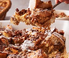 a spoonful of food is being taken out of a casserole dish with powdered sugar on top