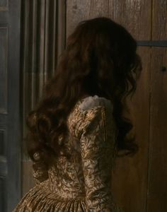 the back of a woman's head in an old fashion dress with long dark hair